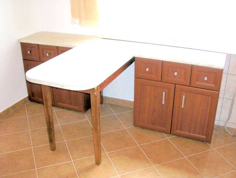 Elz oldalon lév konyhabútorhoz készült étkez asztal fszeres fiókokkal kétajtós szekrényekkel asztal lábai