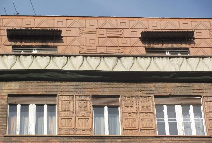 A felette lévő négy szint téglaarchitectúráját markáns műkő párkány zárja. A mészkő burkolat több helyen jelentős mértékben sérült, a téglaburkolat tisztításra, újra fugázásra szorul.