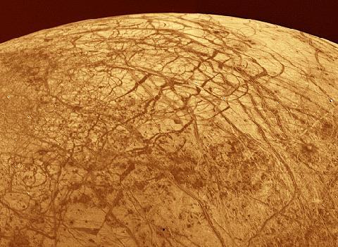 A hold felszíne egy Voyager felvételen. Érdemes felfigyelni a hálózatokra emlékeztető vonalakra. (NASA/JPL.) Itt is érvényesül az árapály-fűtés felszínformáló hatása.