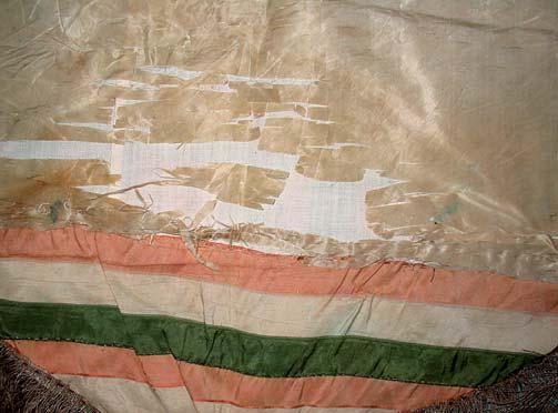 A zászlólapot láthatólag megrövidítették, selyem anyaga szakadt, töredezett, hasadozott, piszkos, nagyon fakult, foltos.