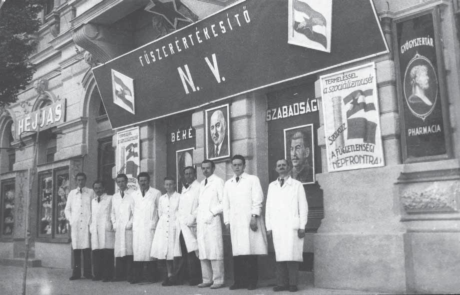 a 39. 1949. május elsejei dekoráció a mai Arany patika helyén lévő Fűszerértékesítő Nemzeti Vállalat üzletének homlokzatán. Az üzlet előtt az alkalmazottak állnak.