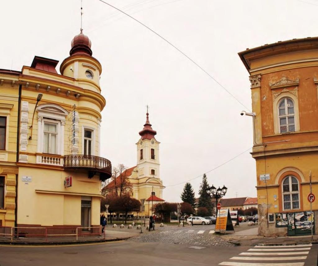 Pohľad c) pohľad z križovatiek ulíc Š. Hatvaniho a Jánošíkovej na Hlavné námestie a r. k. kostol sv. Jána Krstiteľa F.1.3.