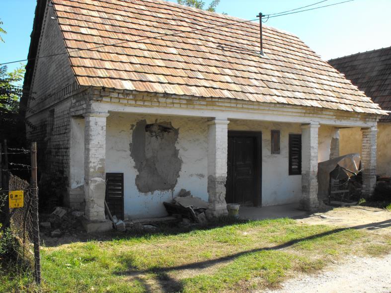 A fehérre festett főhomlokzaton láthatók az ablakok és közöttük a bejárati ajtó.