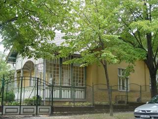 Délre néző íves záródású nyitott homlokfalával az egyik legszebb füredi veranda. A vakolt falak okkersárga színűek, a nyílászárók tokja és kerete fehér.