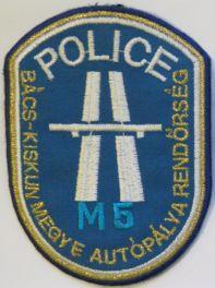 Felső részen "POLICE" felirat fehér színnel, alatt az autópálya nemzetközi jele fehér színnel, alsó részébe kék színnel "M5" felirat került.