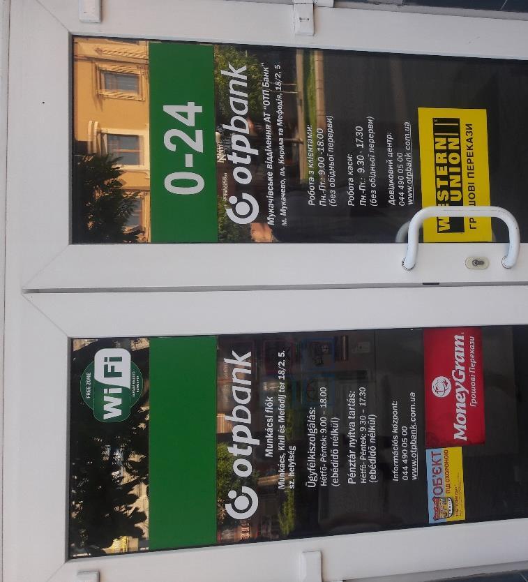 A korzón sétálva szembeötlenek a magyarországi OTP Bank munkácsi fiókjának bejárati ajtaján lévő kétnyelvű feliratok és a nyitvatartási időről szóló információk.
