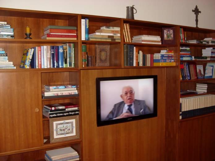 A középen lévő televízión egy riportfilm részlete vetíthető.