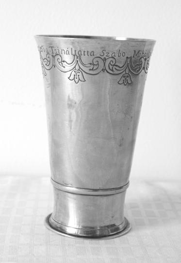 Az Írás ivóeszközről beszél.. III. 59. Talpas pohár Mikepércs Debreceni Egyházmegye Ezüst, vésett díszítéssel, vésett felirattal. Alacsony talpának széle kissé kihajló, felül sima gyűrű zárja.
