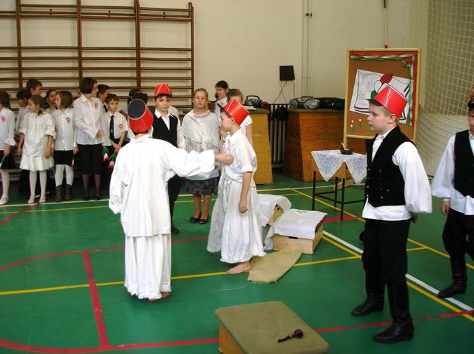 ZENE: KODÁLY: HÁRY JÁNOS TOBORZÓ (A fiúk fejére csákó kerül, táncolni kezdenek. Lemennek a színpadról. Folytatódik a verses keret, a szereplők elhelyezkednek) Fiú: Indul a had, Mind: moccan.