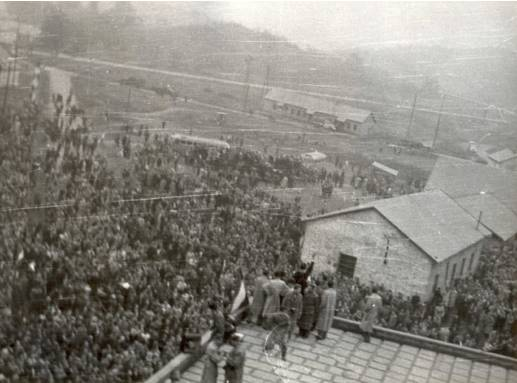1956. október 25. 11 óra 30 körül Az aula tetején álló szervezők, lent a beszédet hallgató munkástömeg. Az aula lapos teteje fölötti sátortőről fényképezve.