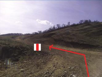 Ezen haladunk 1,84 km-t, továbbra is a piros sáv jelzéseket követve, egészen addig, amíg kiérünk az erdőből egy tisztásra, és egy jelzőoszlophoz érkezünk.