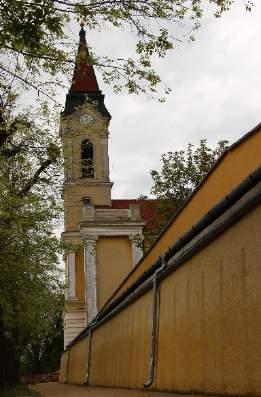 találkozásánál, magaslaton, szabadon álló, keletelt, háromhajós, bazilikális elrendezésű, homlokzati tornyos, a szentély felé kontyolt nyeregtetős templom.