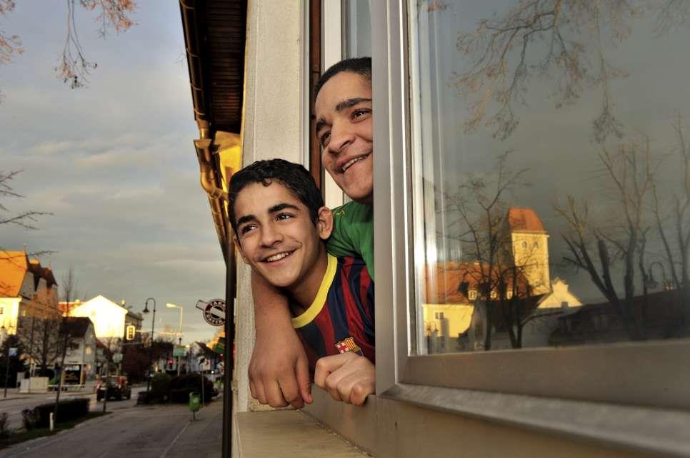 Resettled Syrian refugee children look out of a window at their new home in