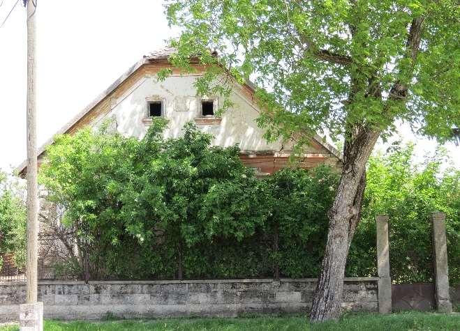 A csonkakontyolt nyeregtetős lakóépület utcai homlokzatán vakolatkeretezéses, zsalugáteres ablakok