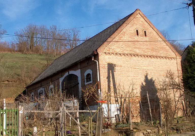 végigfutó rizalit, a nyílászárókat díszítő füleskeret, a homlokzati síkot lezáró diszítősor, valamint zsalugáteres nyílászárói