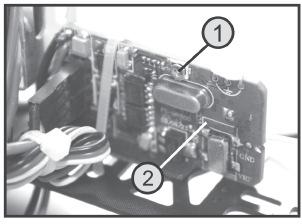 ábra Csavarozza le a hátulról nézve jobboldali irányítókar szerkezetről a retesz rugót (1) és (hátulról nézve) tükrözve csavarozza fel a baloldali irányítókar szerkezeten előkészített tartóra (2).
