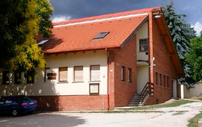 A plébánai a Fő utca és a Szent Imre utca sarkán Az iskola tornacsarnoka és kétszintes épülete a tornaudvar felől.