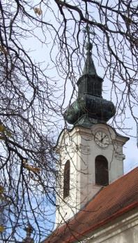 Törtíves zárókővel díszített kőkeretes kapuzata felett szegmensíves, keretezett lapos fülkében festett ikon található.
