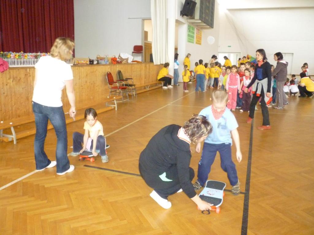 6. feladat: Gördeszkán ülve, nyújtott lábbal gurulás, akadály megkerülése, kézzel segítve a