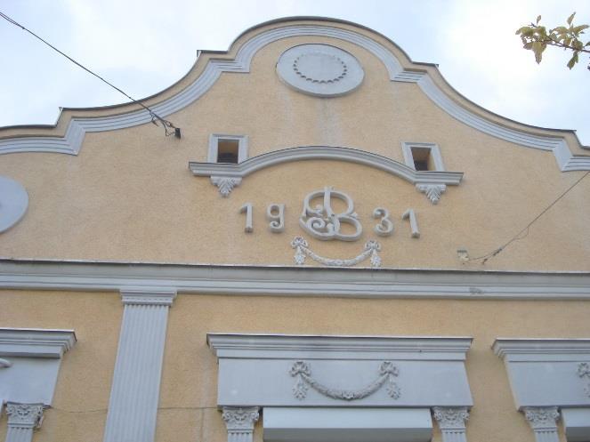 Az íves záródás játékos, a vakolatmezőket fehér ornamentika választja el, utóbbiak a felújítás során sajnos idegen elemekkel is kiegészültek. Állaga megfelelő. A kerítés nem illik hozzá.