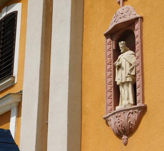 A homlokzatot meghatározza az ajtó fölötti íves nyílás és a tornyon kialakított félköríves záródású, fa zsalugáteres ablak a rajta lévő kereszt díszítéssel. 8.