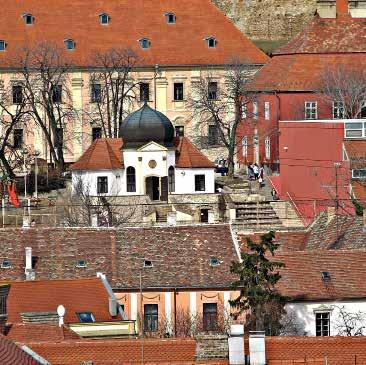 papnövelde épülete, és a templomok tornyai. A város mögött húzódó Misina-hegy ormán álló tv-torony koronázza a látványt.