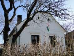 Az oromzaton a két íves záródású, szintén vakolatkeretelt, alul fogsoros kötényrésszel ellátott szellőző közötti vakolattükörben az 1862- es