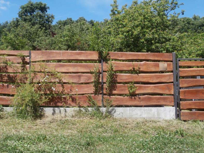 Kovácsoltvas kapu terméskő oszlopokkal.