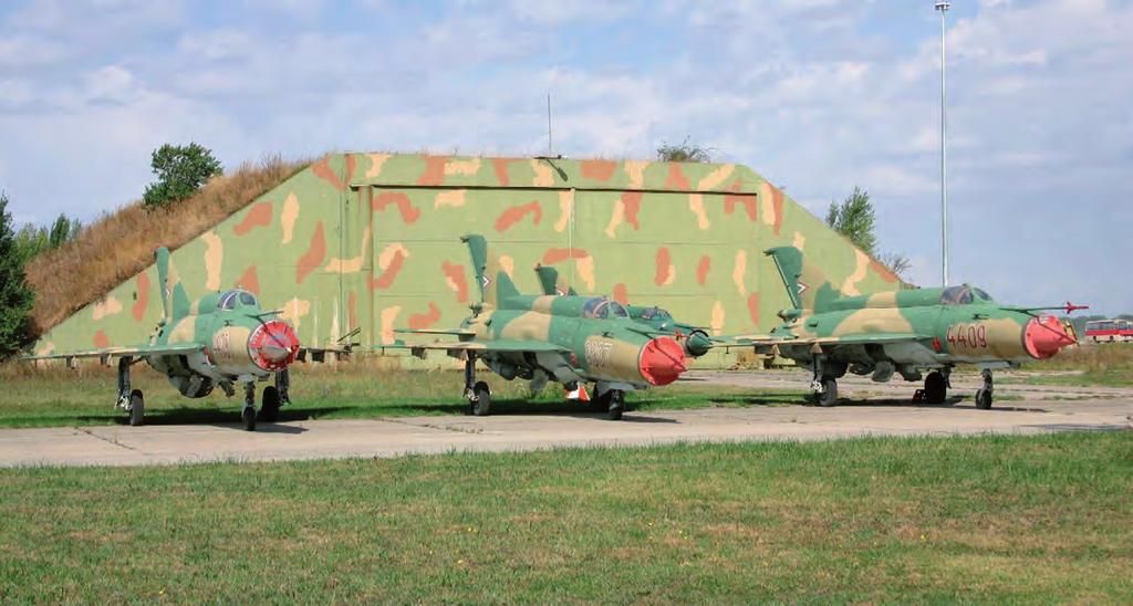 Haditechnika-történet 22. ábra. MiG 21-es harci repülőgépek az egyik tárolásukra és indításukra szolgáló betonfedezék előtt majd újra felszálltam, napnyugtára éppen hazaértem Taszárra.