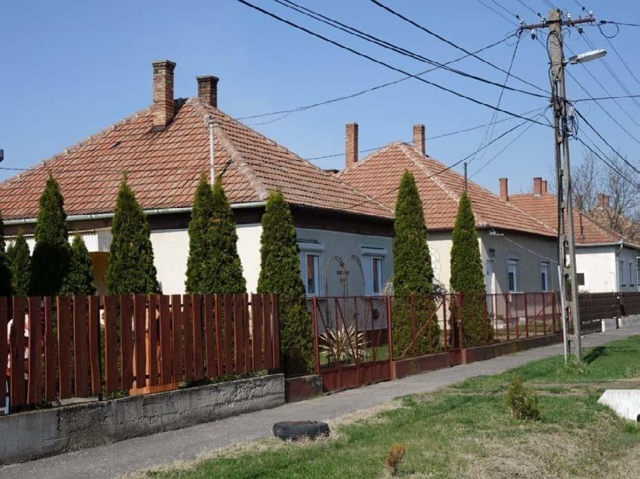 Tetőtérbeépítéses épület visszafogott színvilággal. A kerítésen a főépület díszítőelemeinek színe és anyaga köszön vissza.