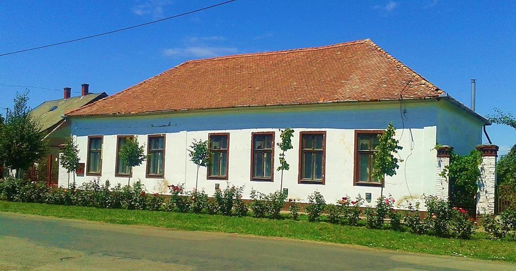 A napsugár motívumos oromzat mellett a kerítés is a hagyományt testesíti meg, akárcsak az utca virágos zöld növényzeti