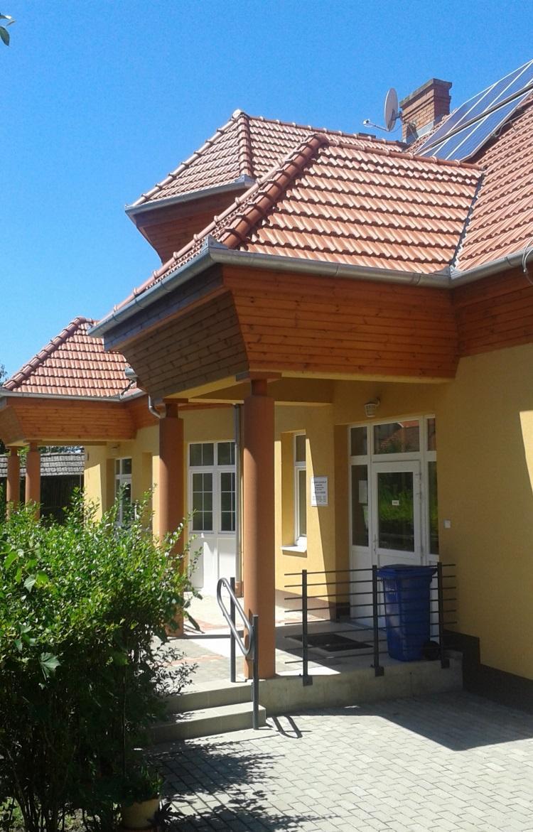 Az épület anyaghasználata, színvilága, a szinte teljesen kontyolt tetővel illeszkedik a településközpont felújított