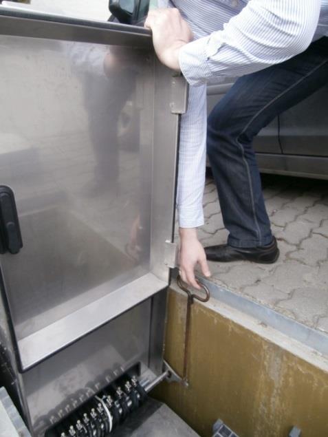 8. kép: Kireteszelés és biztosítás A reteszfogantyút a szabaddá vált kézzel kell megfogni, vagy a fedélemelő kampót beleakasztani (9. kép).