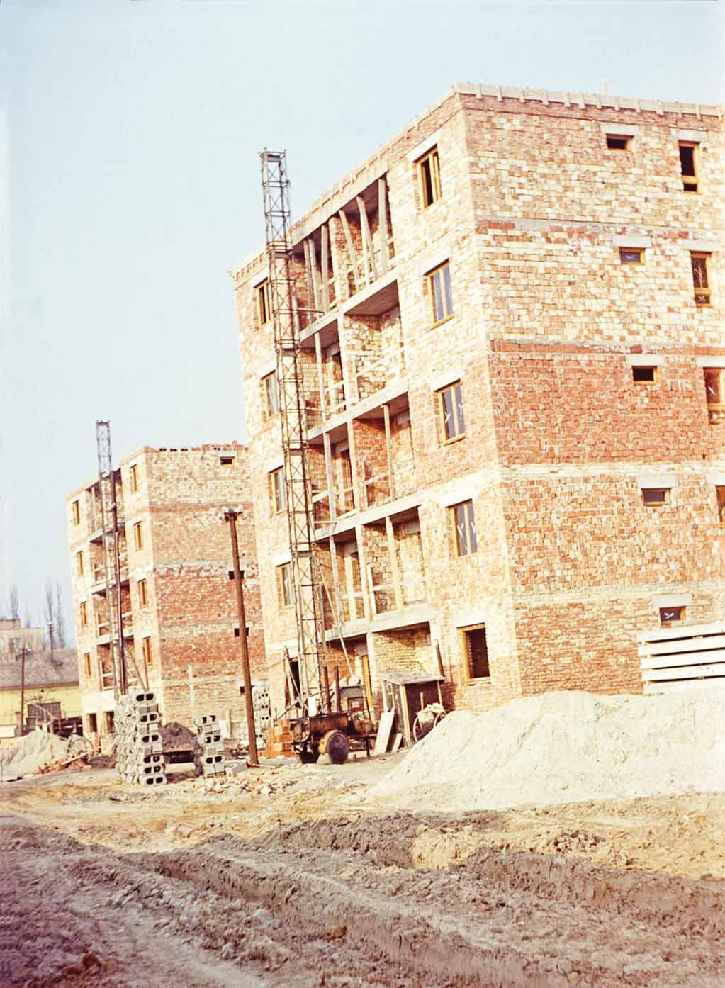 Mögötte a Gát utca páros oldala még félkészen áll. A távolban épül már a Gyopár utca vonalában álló házsor is. a 179. Épülnek a mai Október 23. téri lakótelep 1. és 2.