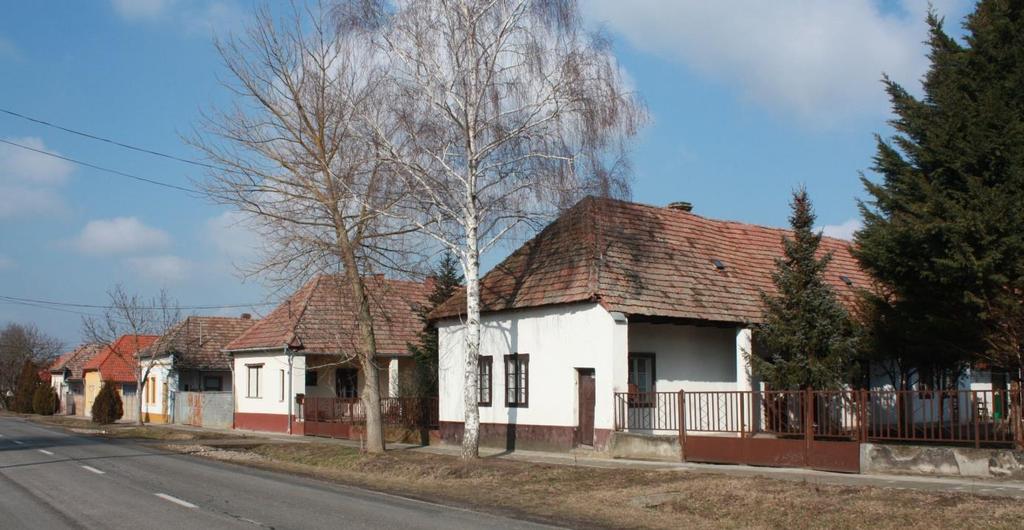 12 A Paksot Cecével összekötő út Paks felől derékszögű kanyarokkal halad át a településen. Az első építmény, ami feltűnik a kicsit a múltból itt ragadt benzinkút képe.