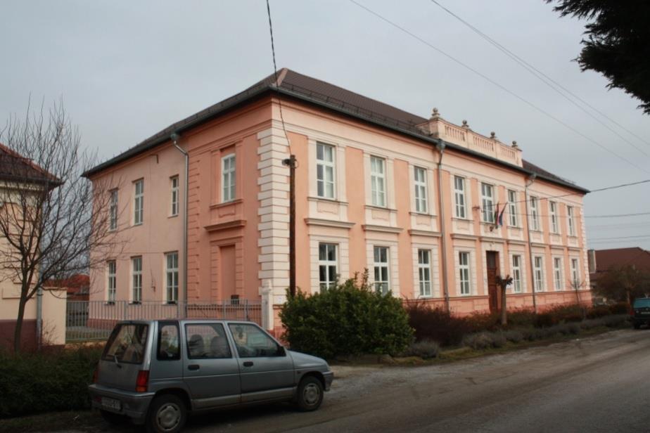 Az egyszerű, egyenes gerincű, hagyományos hajlásszögű tető a sima rajzolatú kerámia fedéssel, a faburkolatos oromfal, az utcára néző két ablak, az oszlopokkal gyámolított,