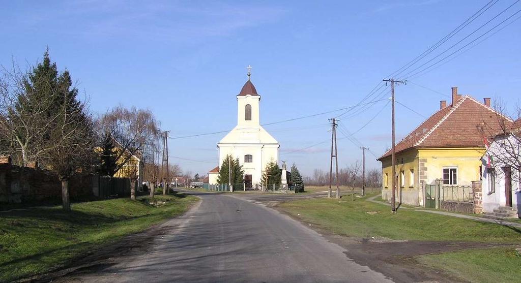 A katolikus templom a falu Fő utcájának északi végén, egy Y alakú elágazás csúcspontjában, az utca tengelyében áll, a harangtorony pedig a