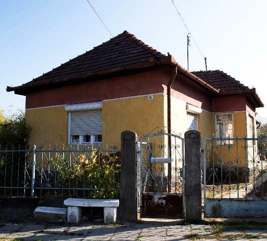 E hosszúkás, az utcára merőleges irányultságú, téglalap alaprajzú épületeket általában egyszerű kontyolt nyeregtető fedi és a tetősíkot csak a vakolatlan téglakémény látványa töri meg.