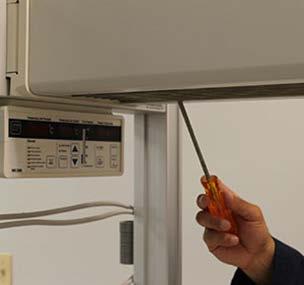 10. Pass the tip of a long Phillips screw driver through the heater grille at an angle to engage the back reflector screw, and then use a wrench or nut driver to loosen the nut about one turn (Figure