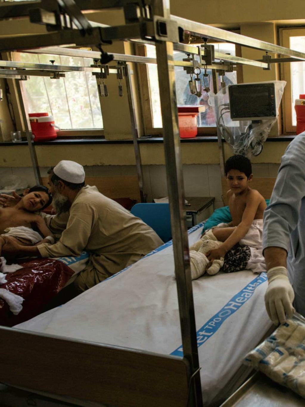 Hamisha Gul tries to comfort his son Mangal, at left, after the painful daily cleaning process at Nangarhar Regional Hospital on